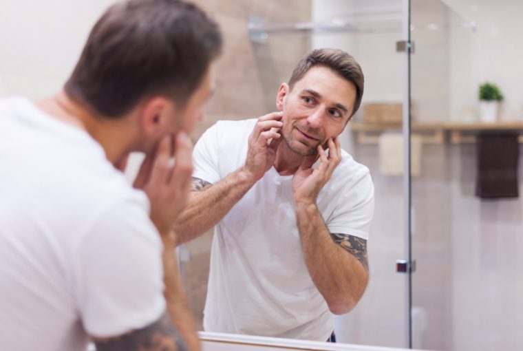Man check condition of his skin in mirror reflection